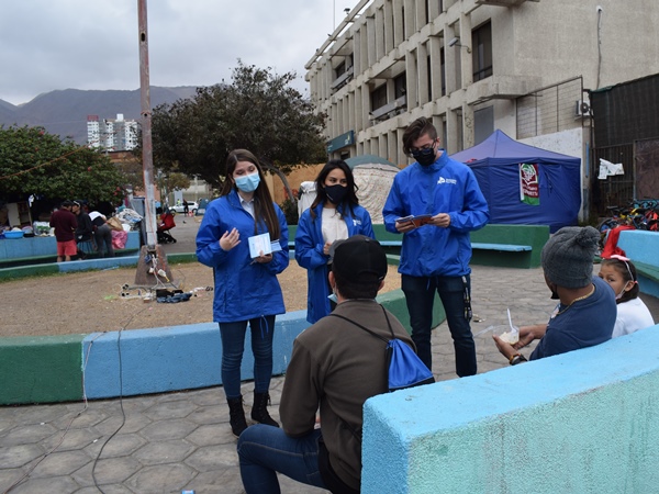 El equipo de la Defensor&iacute;a de Tarapac&aacute; conversando con personas migrantes acampadas en la plaza "Brasil" de Iquique.