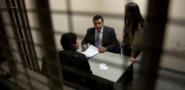 Defensor juvenil y asistente social atendiendo a un joven imputado