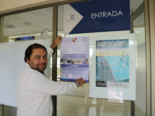 El jefe de la nueva oficina de defensa penal ind&iacute;gena, Rodrigo Torres, instalando el material de difusi&oacute;n en el TOP de Arica.