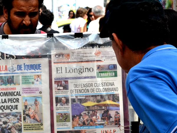 Transe&uacute;ntes leen los titulares de los diarios regionales de hoy, expuestos en los kioskos de Iquique.