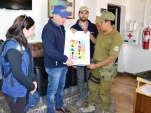 Un carabinero de guardia recibe el material de difusi&oacute;n de manos del Defensor Regional de Tarapac&aacute;